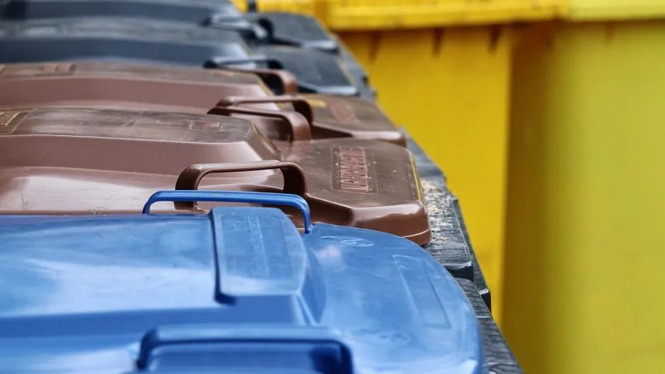 Blick auf Mülltonnen unterschiedlicher Farben - Papier (blau), Biomüll (braun), Plastik (gelb), Restmüll (dunkelgrau)